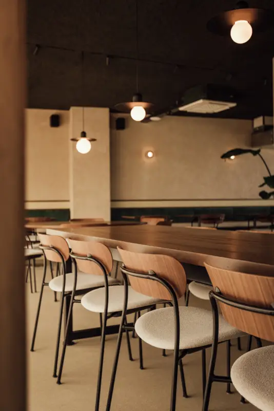 strefa restauracyjna Tilia z banquette w zielonym aksamicie - pendanty Modular Placebo Track 48V Suspended Black, szynoprzewód Pista Track 48V na suficie z wełny drzewnej