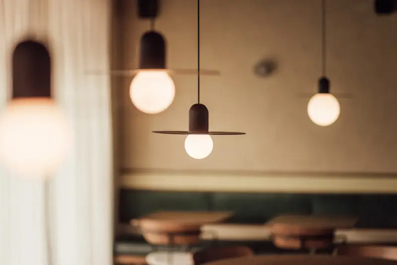 detal pendantów Modular Placebo Track 48V Suspended Black nad bankiet z zielonym aksamitem - oświetlenie restauracji